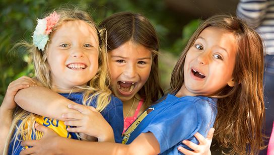 Three young girls hugging and laughing