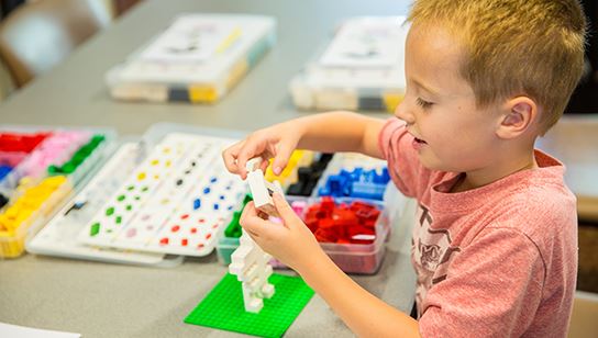 A boy working with Legos at a summer camp